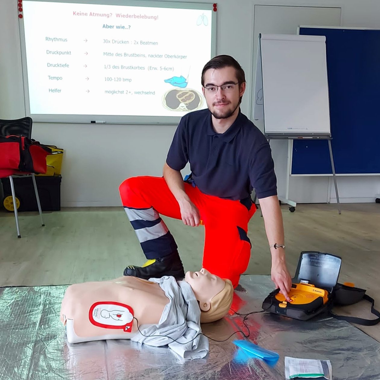 Ein Sanitäter demonstriert Erste-Hilfe-Maßnahmen inkl. AED an einer Übungspuppe in einem Raum der für Notfalltrainings genutzt wird.
